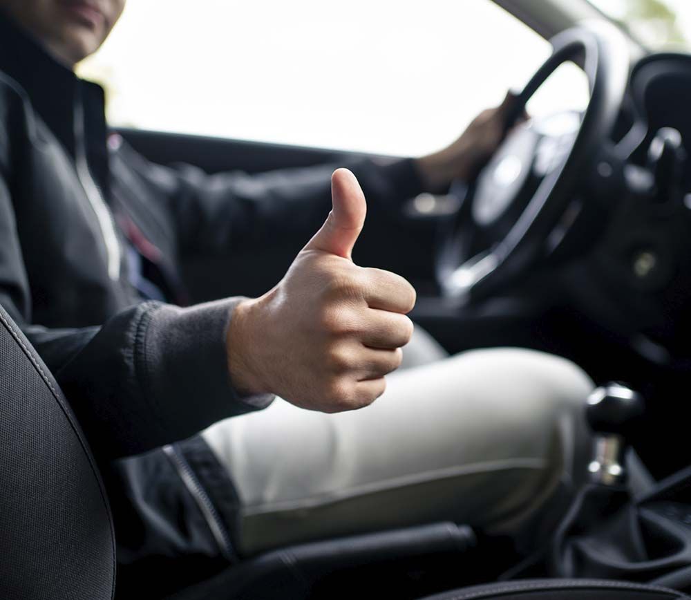 Un hombre en un coche levanta el pulgar.