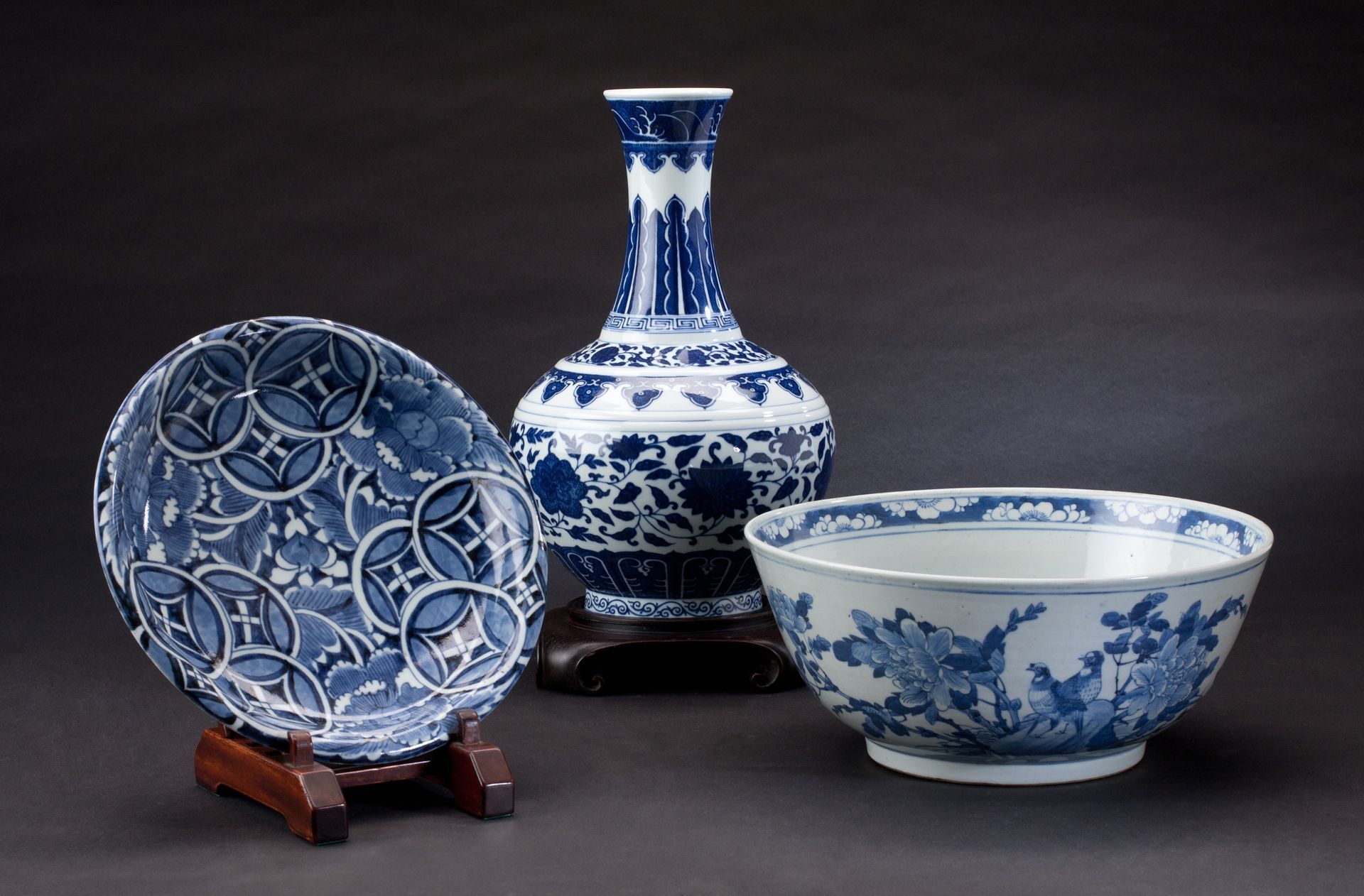 Vase, bol et assiette en porcelaine bleue et blanche présentés sur fond sombre