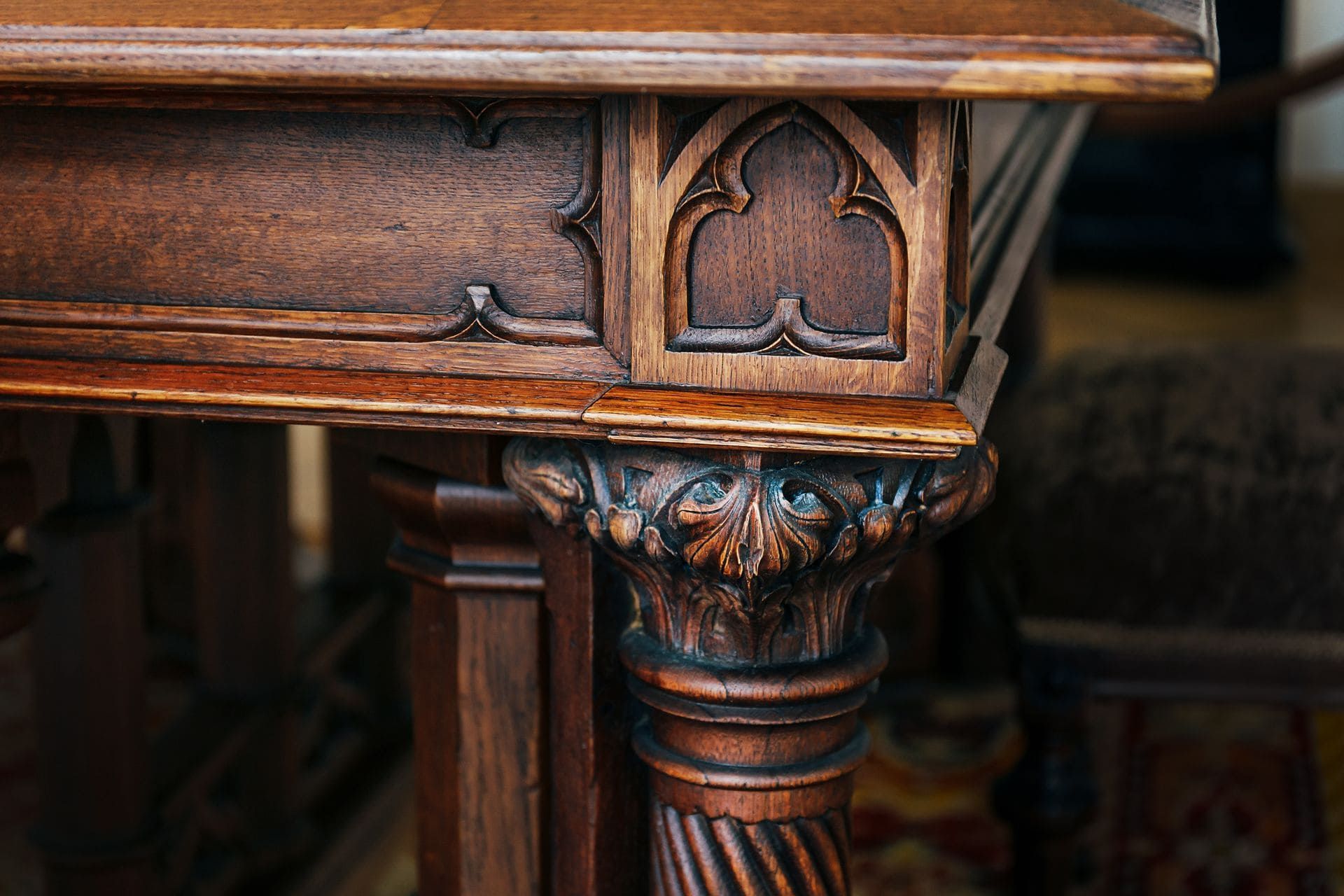 Gros plan sur un pied de table en bois sculpté et orné, avec des détails brun foncé