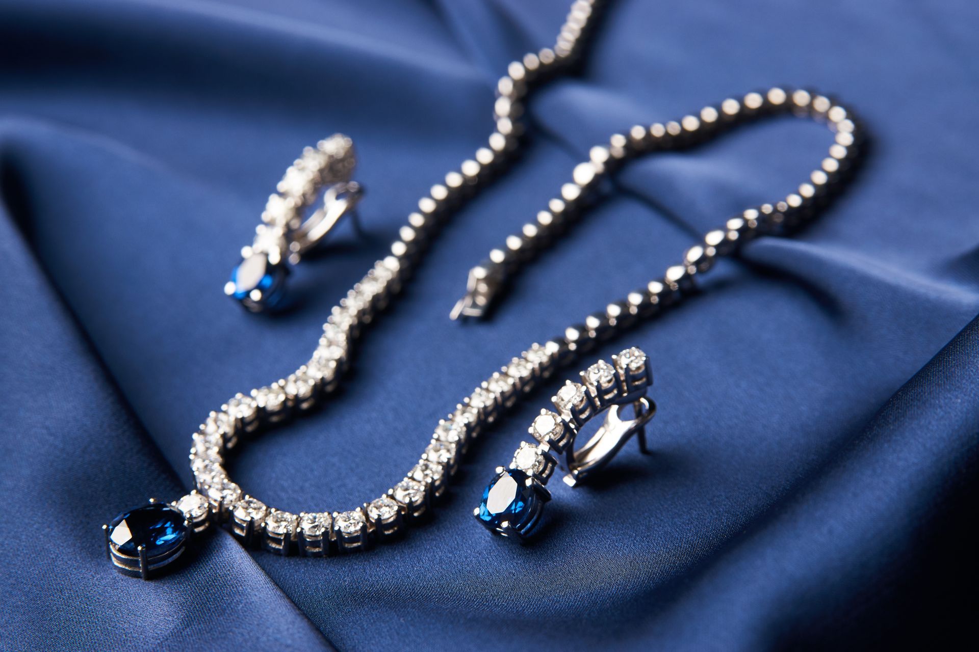 Collier de perles avec boucles d'oreilles en pierre précieuse bleue sur tissu de satin bleu