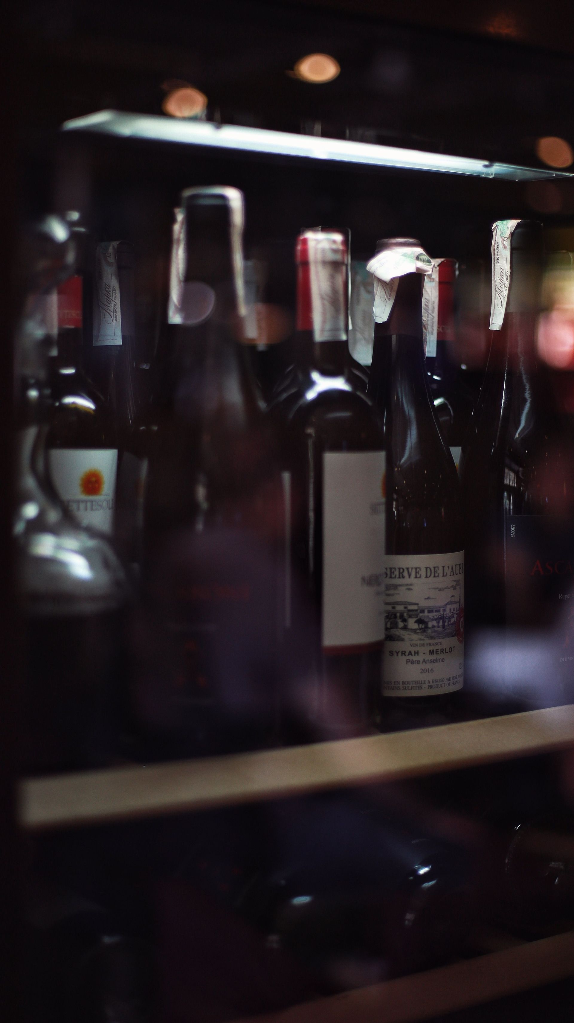 Des bouteilles de vin exposées derrière des vitrines dans une boutique ou un bar à l'éclairage tamisé.