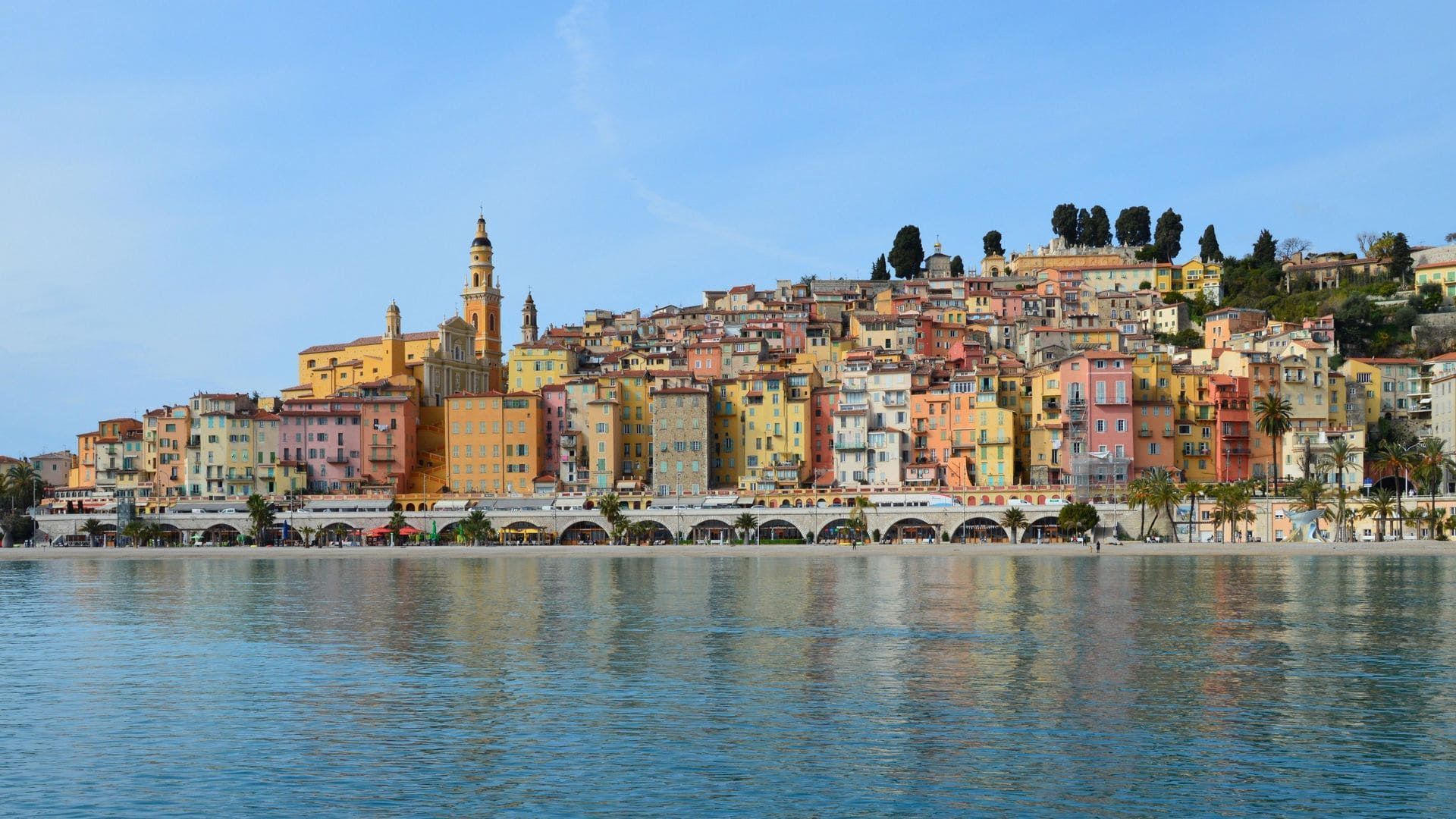 Ville balnéaire colorée avec un clocher le long d'un front de mer calme sous un ciel clair