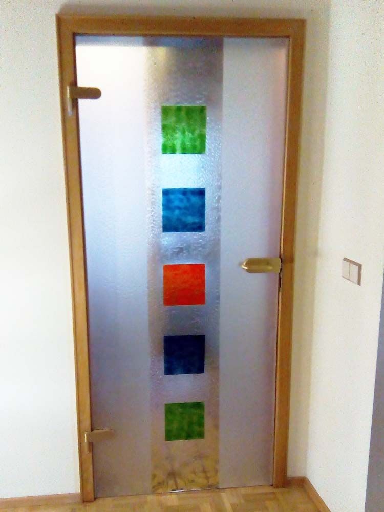 Milchglastür mit Holzrahmen und bunten quadratischen Akzenten im Flur.