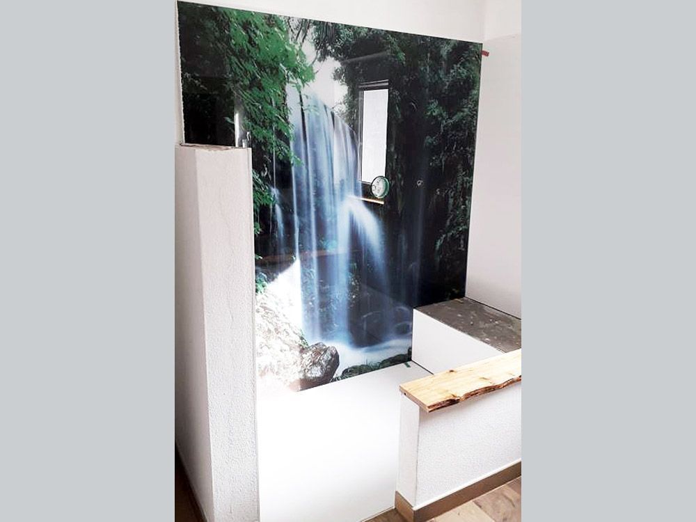 Zimmer mit Wasserfall-Wandbild, weißen Wänden, Holzbank.