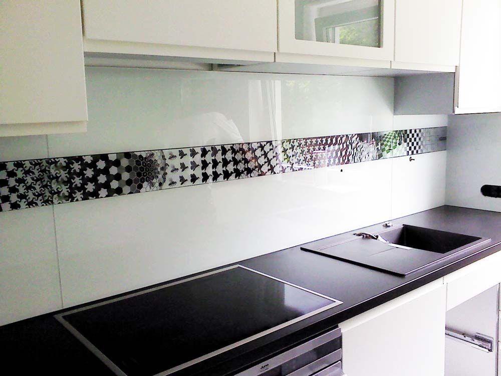 Moderne Küche mit schwarzen Arbeitsplatten, weißen Schränken und dekorativer Küchenrückwand.