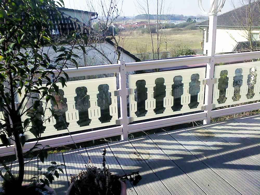 Weißes Balkongeländer mit Milchglasplatten und Blick auf die Landschaft.