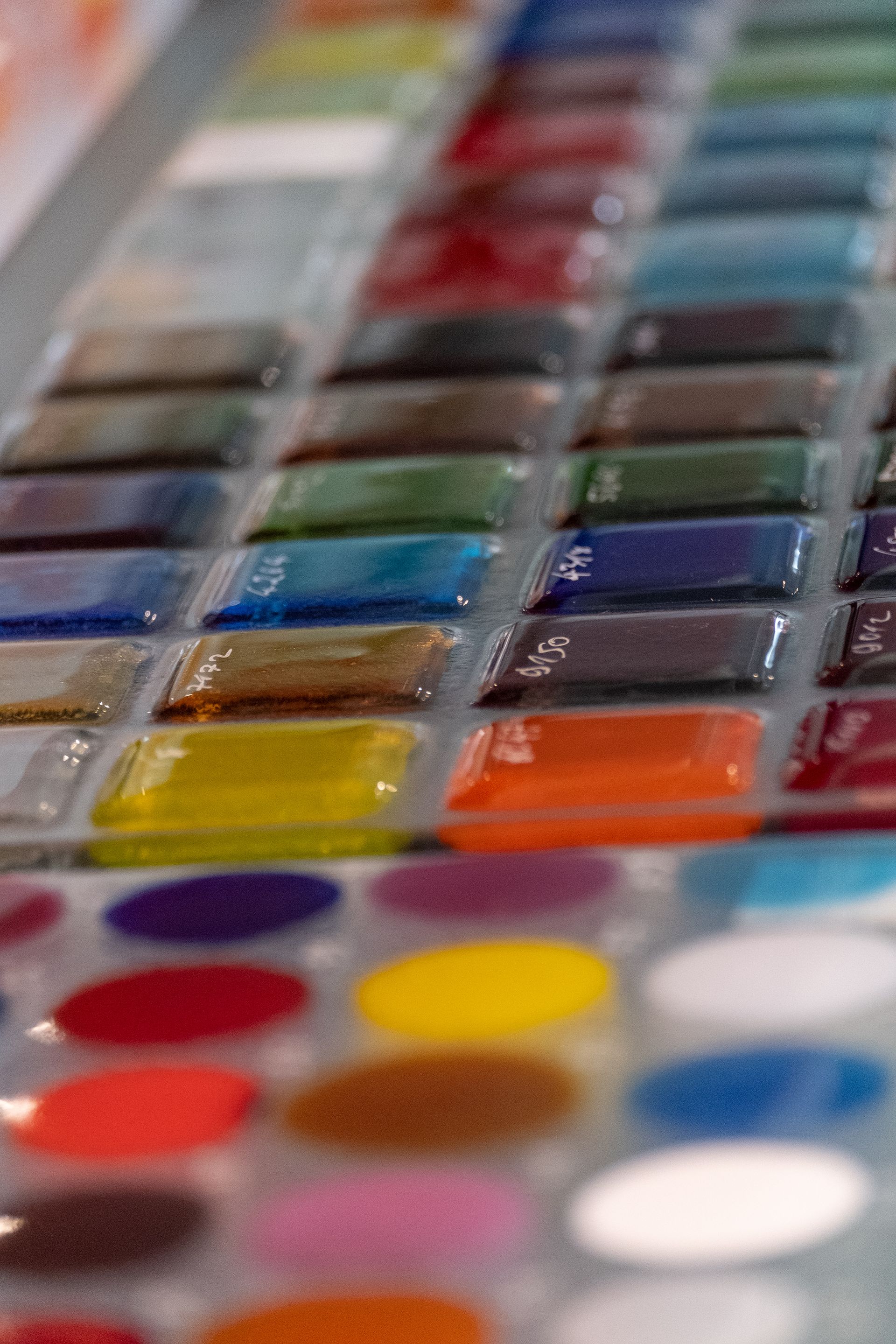 Reihen von farbigen Glaskacheln und Farbproben in verschiedenen Nuancen.