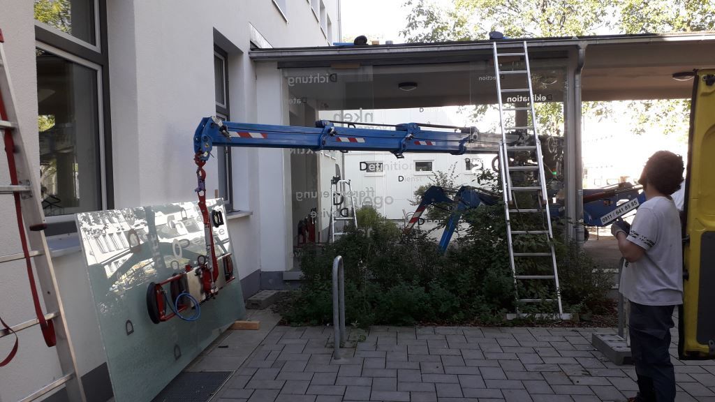 Ein Arbeiter bedient einen Kran, wahrscheinlich zum Fensteraustausch, in der Nähe eines Gebäudes.