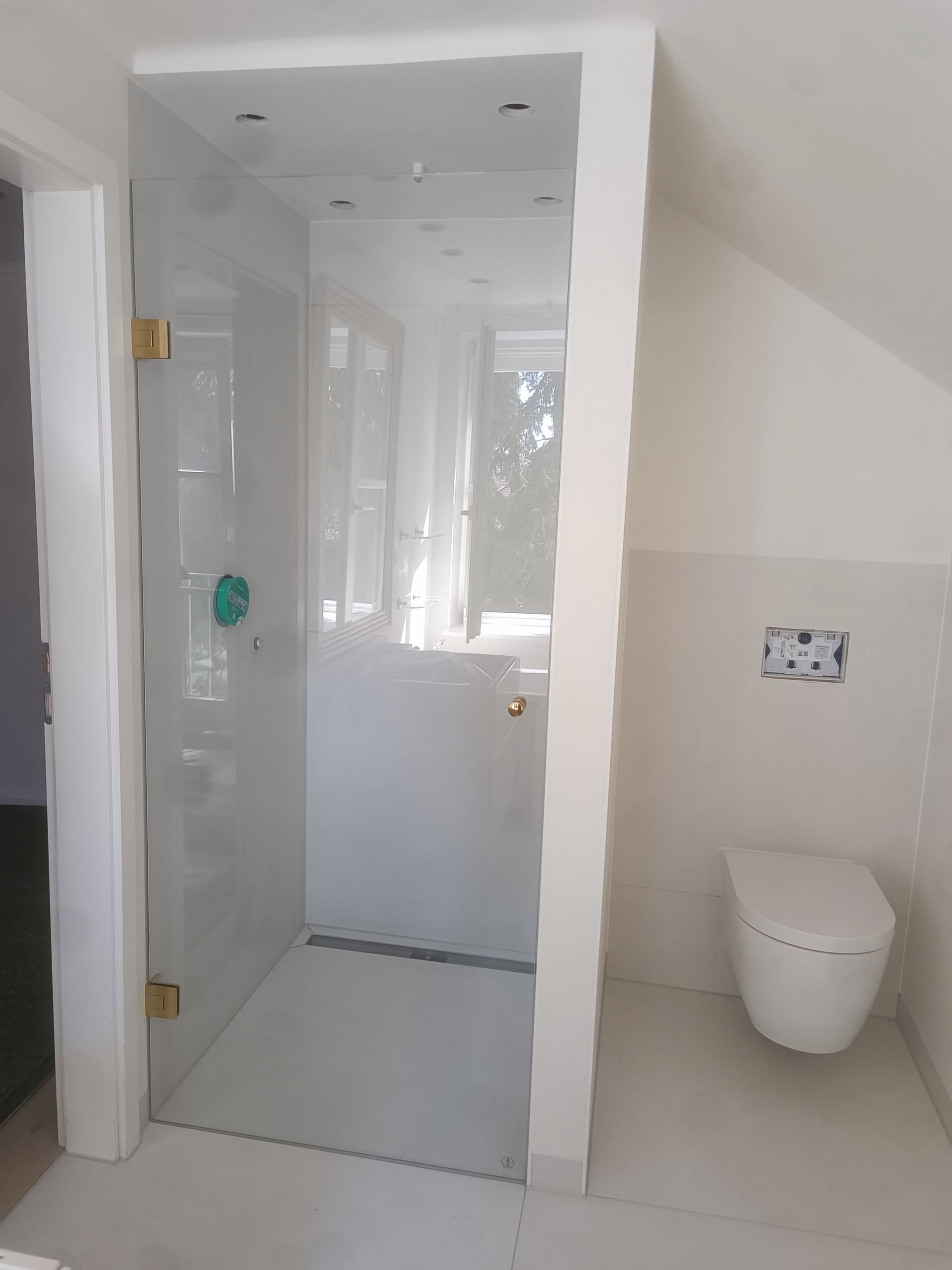 Modernes weißes Badezimmer mit Glasdusche, Toilette und Wandarmaturen.