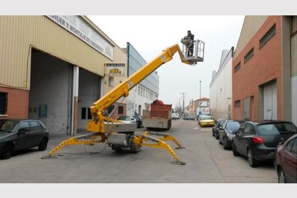Un elevador araña amarillo está estacionado frente a un edificio.
