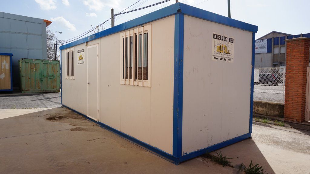 Un contenedor blanco y azul está en el suelo en un estacionamiento.