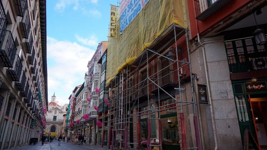 Una calle estrecha con andamios al costado de un edificio.