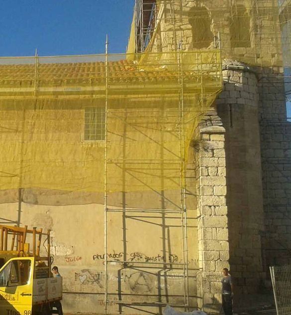 Un camión amarillo está estacionado frente a un edificio en construcción.