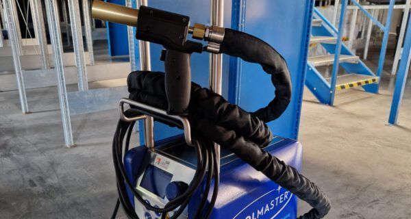 Schwarzes, am Lenker montiertes Gerät mit umwickeltem Kabel an einer blauen Maschine in einer industriellen Umgebung