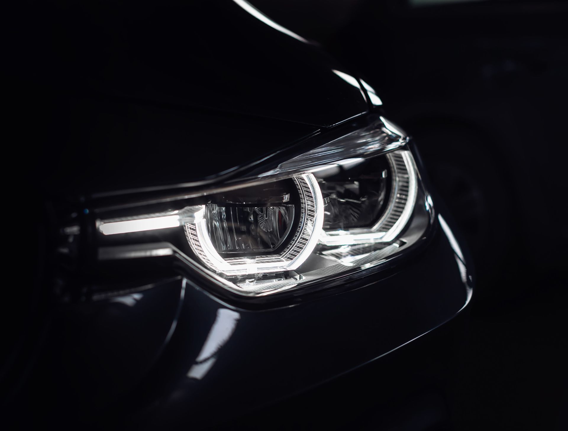 Primer plano del faro LED encendido de un coche negro por la noche