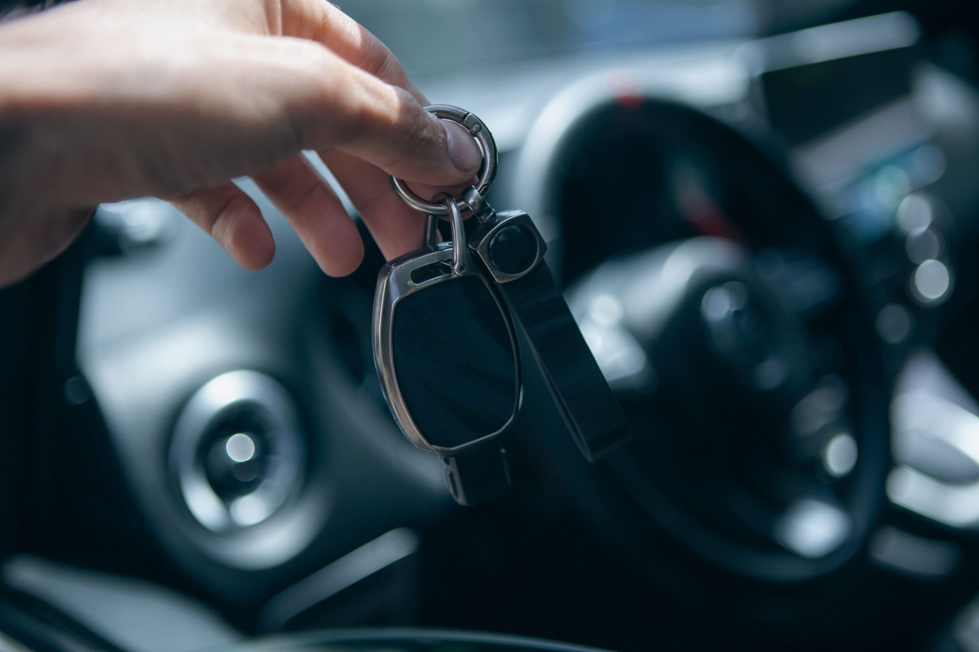 Una mano sosteniendo las llaves del coche dentro de un vehículo, con el volante desenfocado al fondo