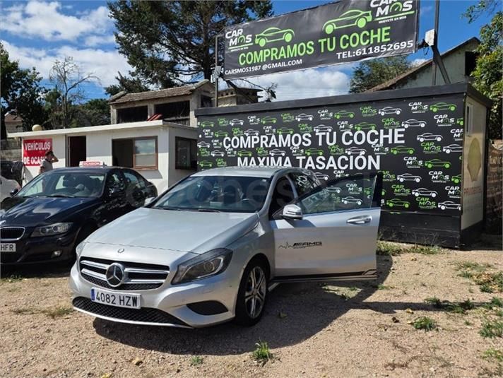 Mercedes-Benz plateado frente a un local de compraventa de coches con un letrero que dice «Compramos tu coche» 