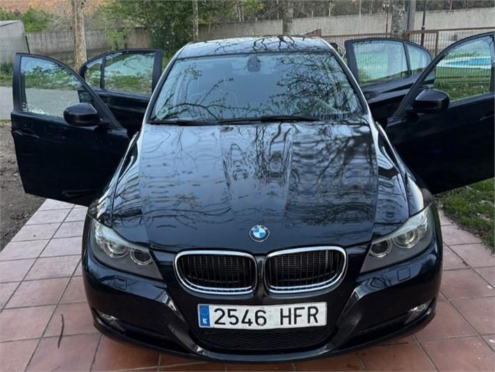 Vista frontal de un BMW negro con las dos puertas delanteras abiertas, estacionado al aire libre