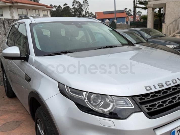 SUV Land Rover Discovery plateado estacionado al aire libre en una entrada, visto desde el frente y el lado izquierdo