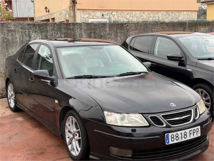 Sedán Saab negro estacionado al aire libre junto a otro coche, visto desde el frente y el lado izquierdo