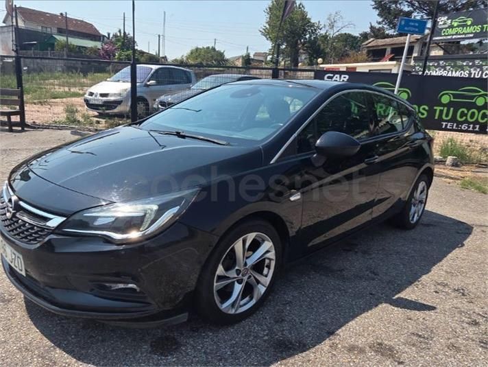 Sedán negro estacionado al borde de la carretera, a plena luz del día, cerca de señales y edificios
