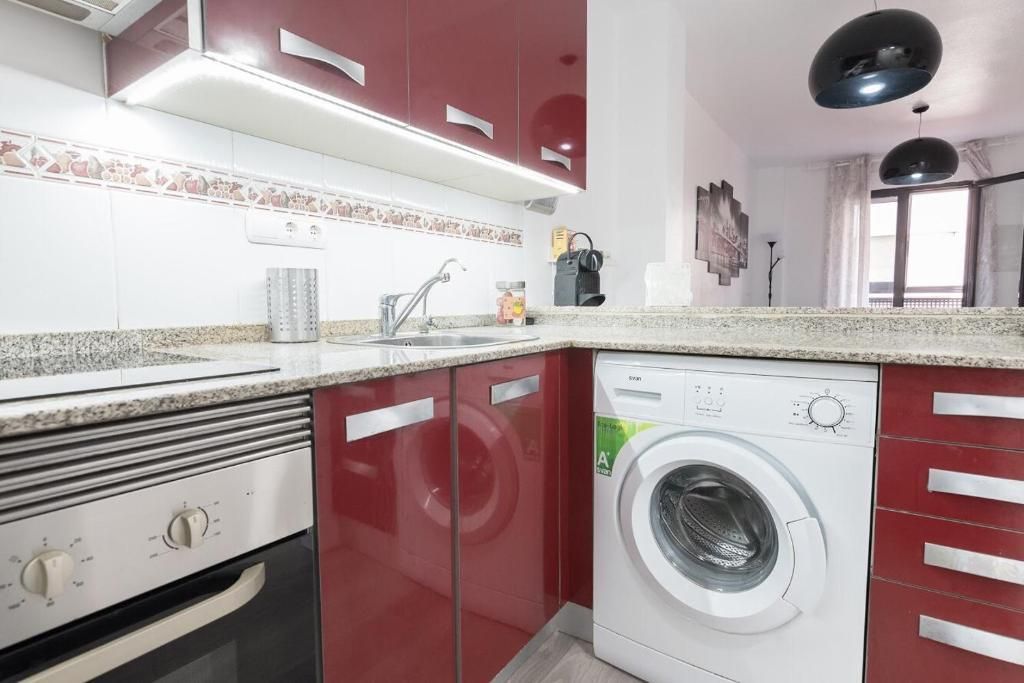 Cocina en color rojo y blanco con electrodomésticos, incluida lavadora y horno.
