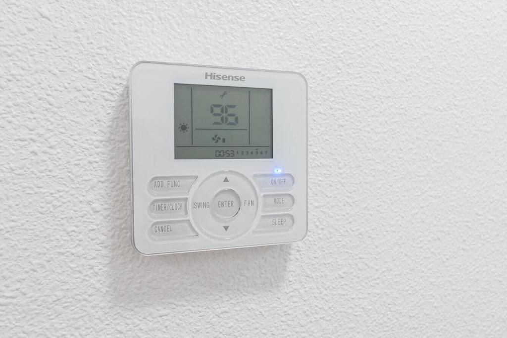 Termostato digital blanco que muestra 95 grados Fahrenheit, montado en una pared blanca texturizada.