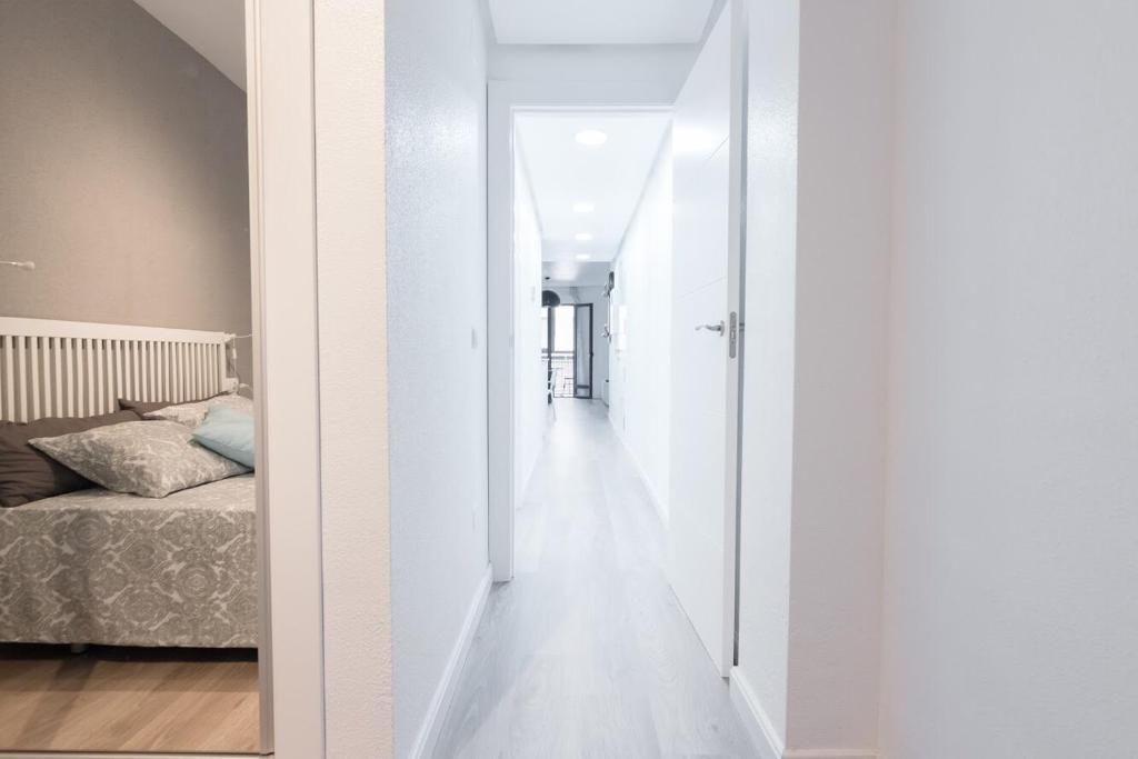 Un pasillo con paredes y puertas blancas, que conduce a un dormitorio a la izquierda.