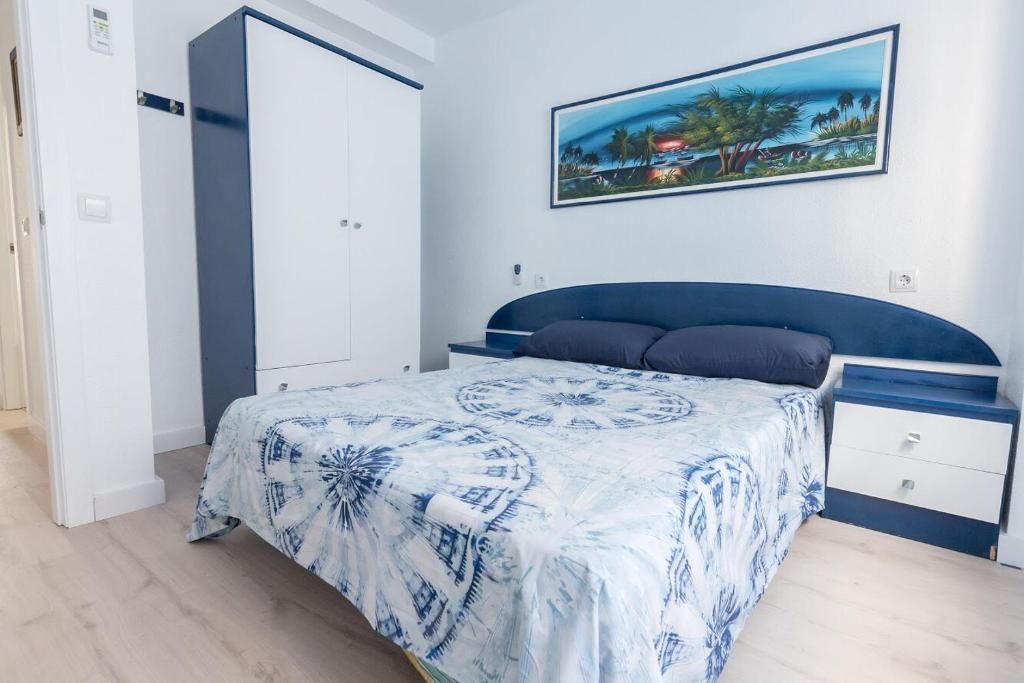 Dormitorio con detalles en azul y blanco; cama, armario, cuadro de un paisaje.