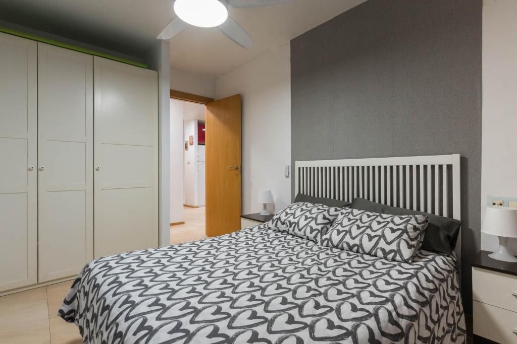 Dormitorio con cama, ropa de cama estampada, armario blanco y pared con acento gris.