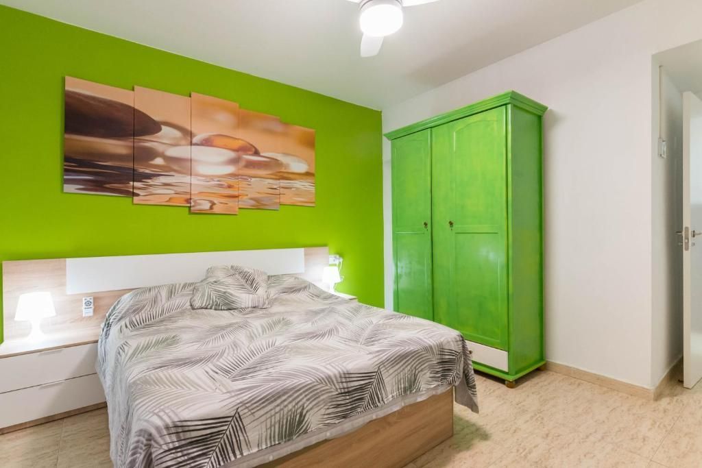 Dormitorio con una pared con acento verde lima, cama, armario verde a juego y arte abstracto.