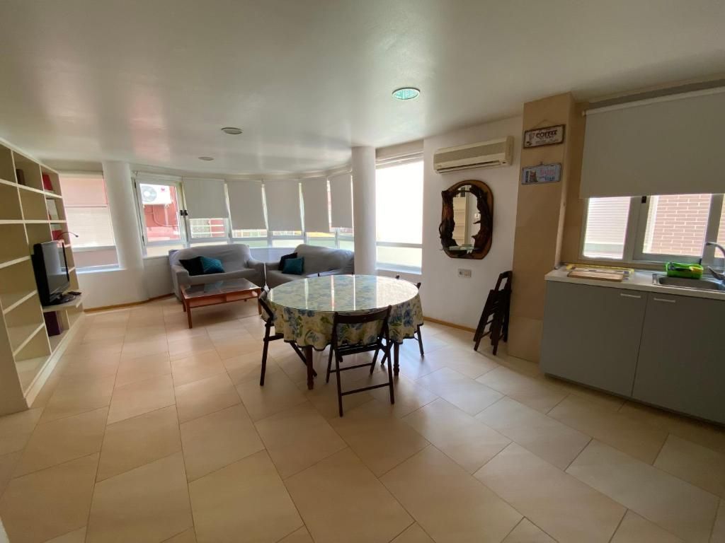 Espacio habitable de concepto abierto con zona de estar, mesa de comedor, estantes empotrados y área de cocina, con ventanas.