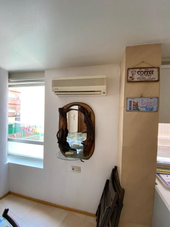 Una habitación con espejo, aire acondicionado y carteles en la pared.