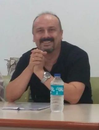 Un hombre está sentado en una mesa con una botella de agua.