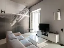 Sala de estar moderna con muebles blancos, gran mural de Star Wars y luz natural.