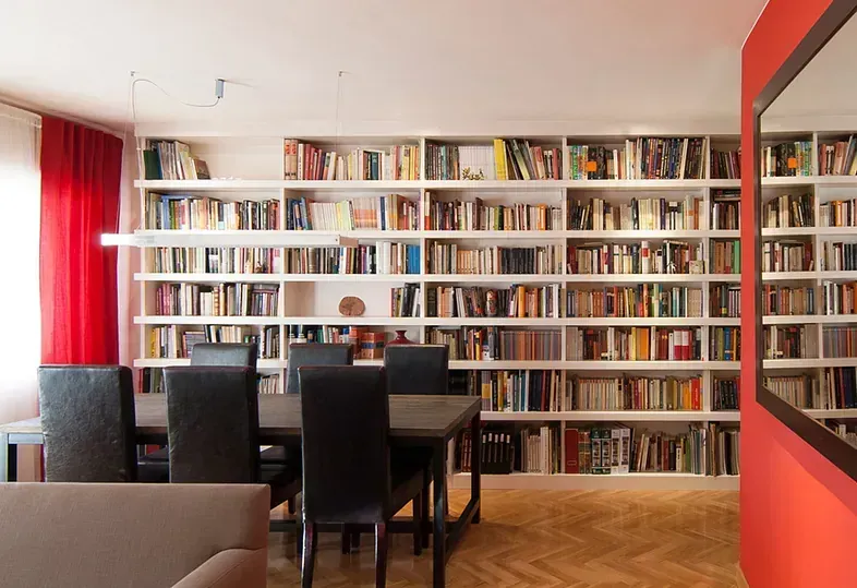 Comedor con estantería grande, mesa negra y detalles de pared en color rojo.