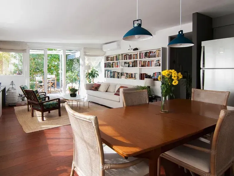 Sala de estar con comedor, sofá blanco, estantería y salida a patio.