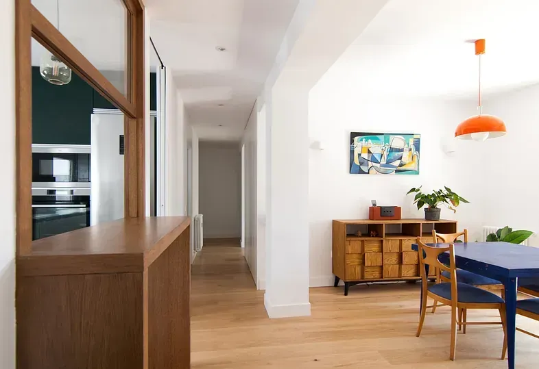 Mueble y mesa de madera en comedor moderno y luminoso, con vista al pasillo.