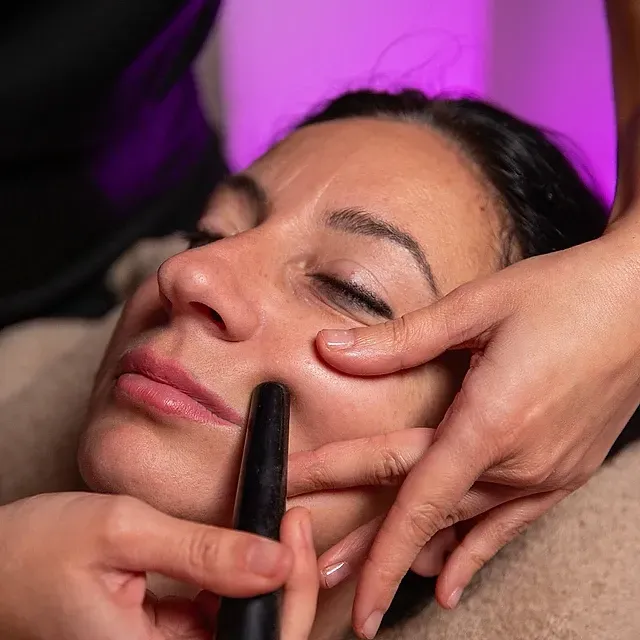 Una mujer está recibiendo un masaje en la cara con un palo.