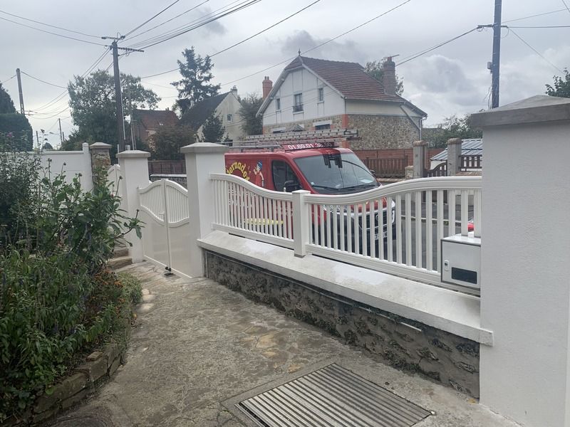 Camionnette de secours rouge garée derrière une clôture blanche dans une allée résidentielle par temps couvert