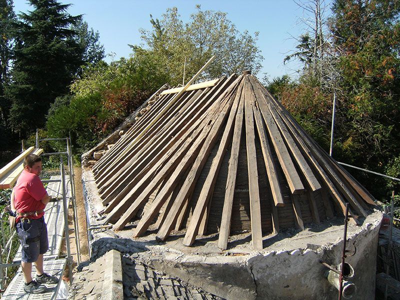 Structure conique en bois en construction, un ouvrier se tenant à côté à l'extérieur.