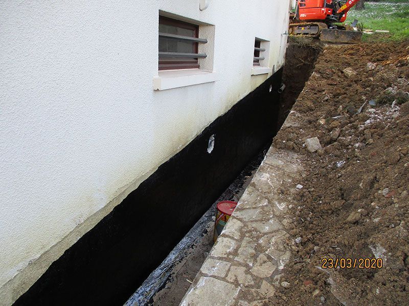 Mur de maison avec une longue tranchée sombre à côté, près d'un site de fouilles rocheuses