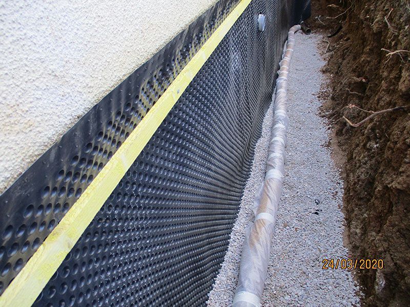 Ruban de signalisation jaune au-dessus d'une barrière anti-limon noire le long d'une étroite tranchée de gravier sur un chantier de construction