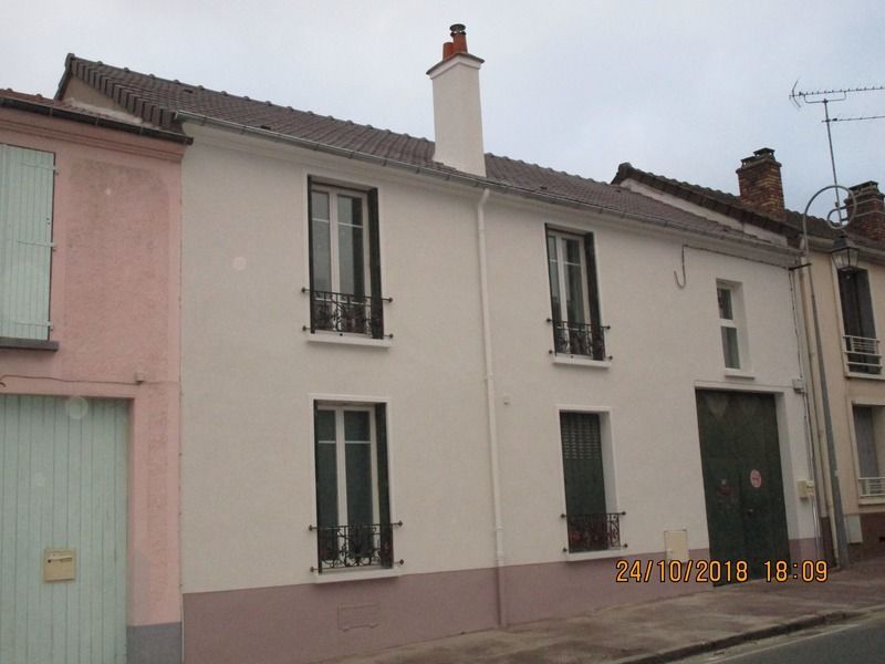 Rangée de maisons étroites à deux étages, aux façades pastel et aux fenêtres à volets, dans une rue calme.