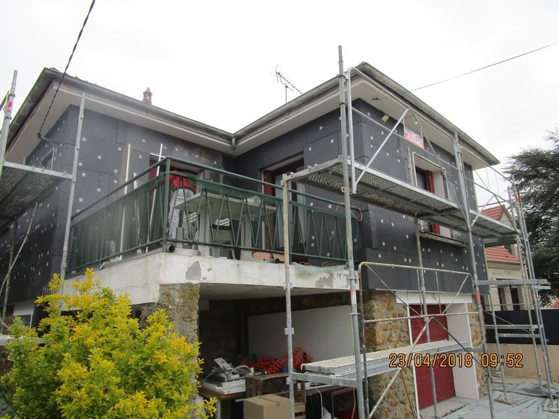 Maison à deux étages en construction avec échafaudages et balustrades de balcon vertes