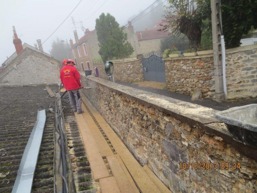 Ouvrier rénovant une mur en pierre.
