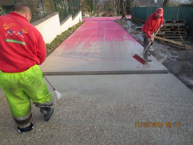 Deux ouvriers étalent du béton rose sur une dalle d'allée extérieure