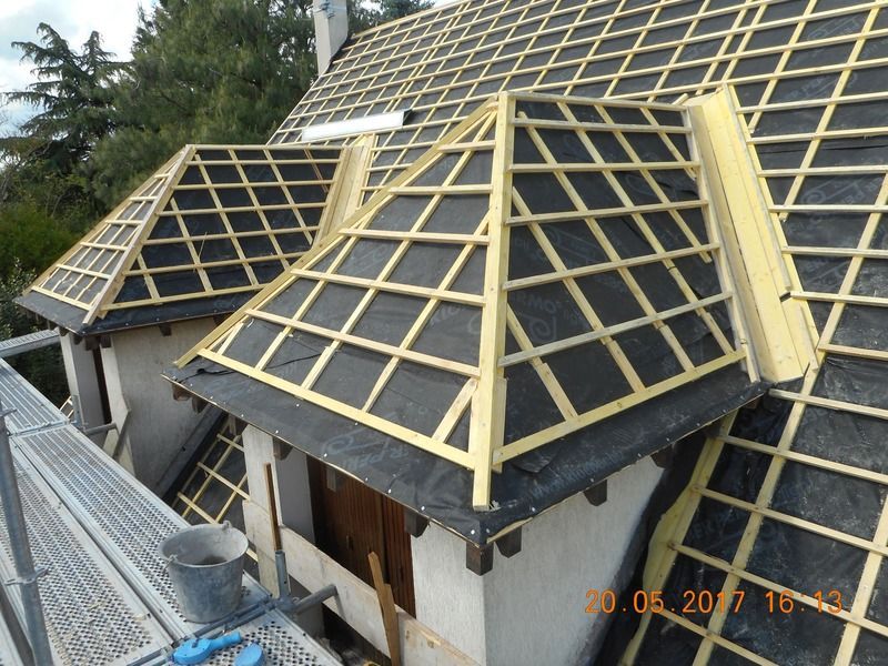 Toiture de maison en construction avec charpente jaune et panneaux de toiture noirs