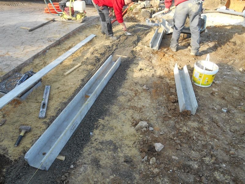 Des ouvriers installent des poutres métalliques sur un chantier boueux.