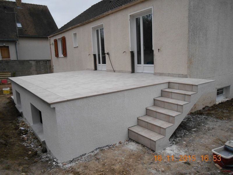 Terrasse surélevée avec escalier à côté d'une maison, zone de construction extérieure non aménagée